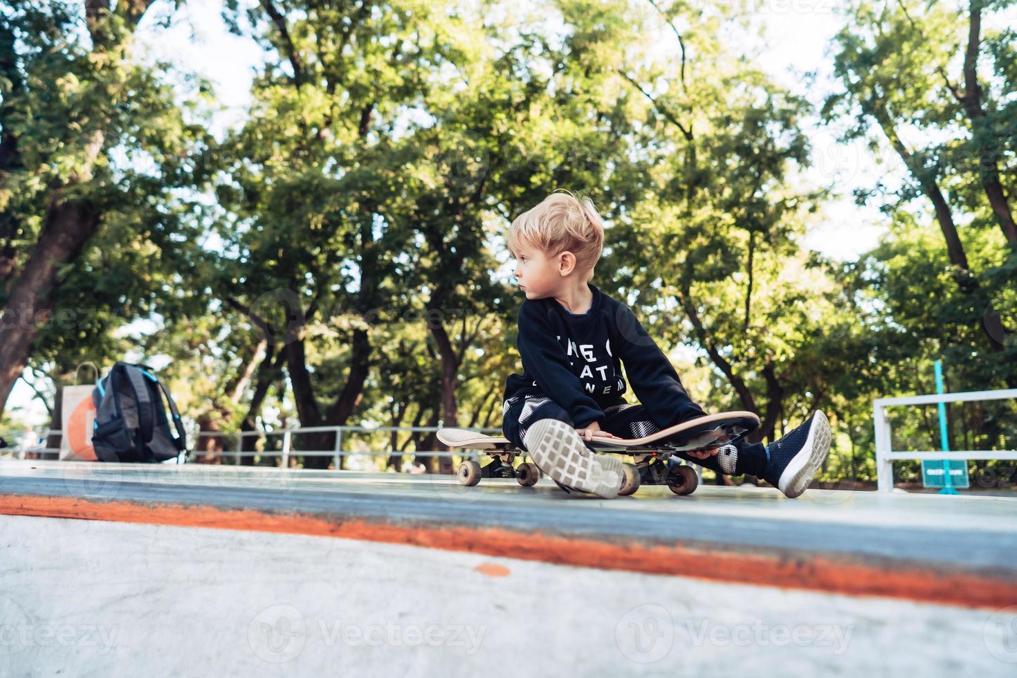 Young kid sitting in the park on a skateboard. photo