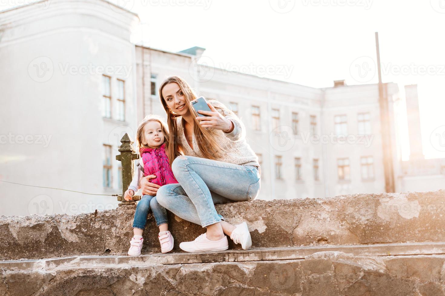 mamá e hija se sientan juntas en la cerca foto