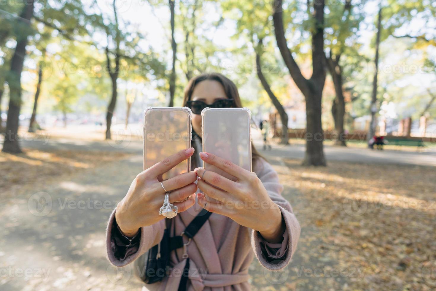 hermosa joven tiene en sus manos dos teléfonos inteligentes foto