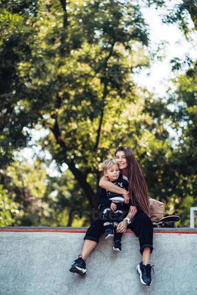 Beautiful young hipster mom and little son at the skatepark photo