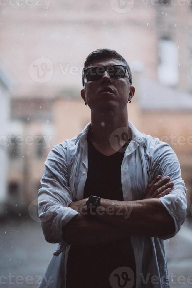 Portrait of carefree handsome young man is feeling free under the rain photo