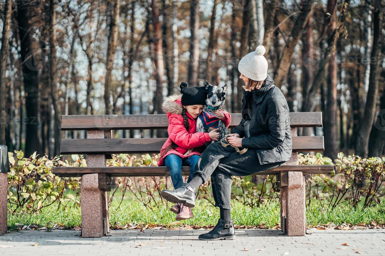 Happy mother and her daughter with dog resting on a bench photo