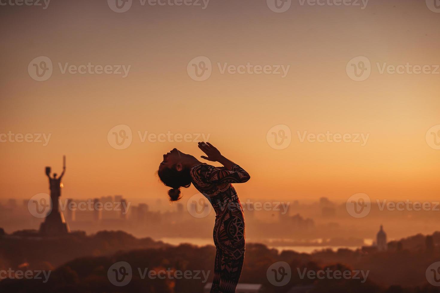 mujer haciendo yoga en la azotea de un rascacielos en la gran ciudad. foto