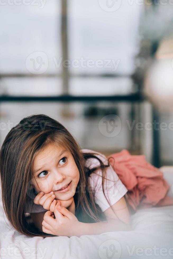 Little girl lying in the bed looking away. photo