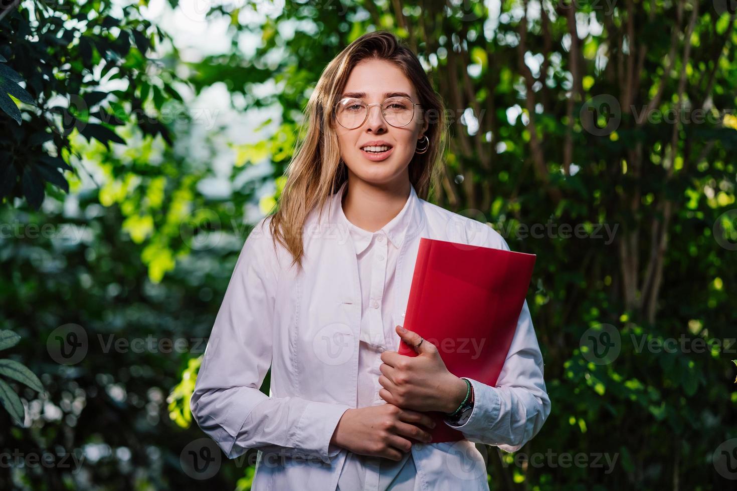 Young agricultural engineer working in greenhouse. Young female scientist looking at the camera photo