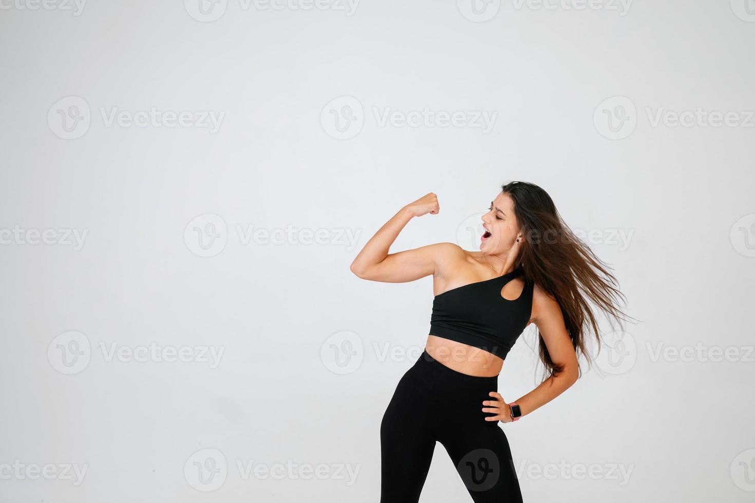 Cheerfully beautiful smiling sporty woman demonstrating biceps photo