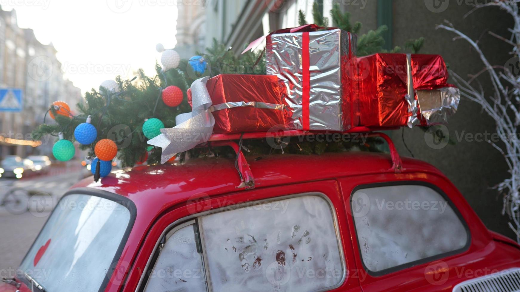 Red retro car with a Christmas tree fir tied to the roof. photo