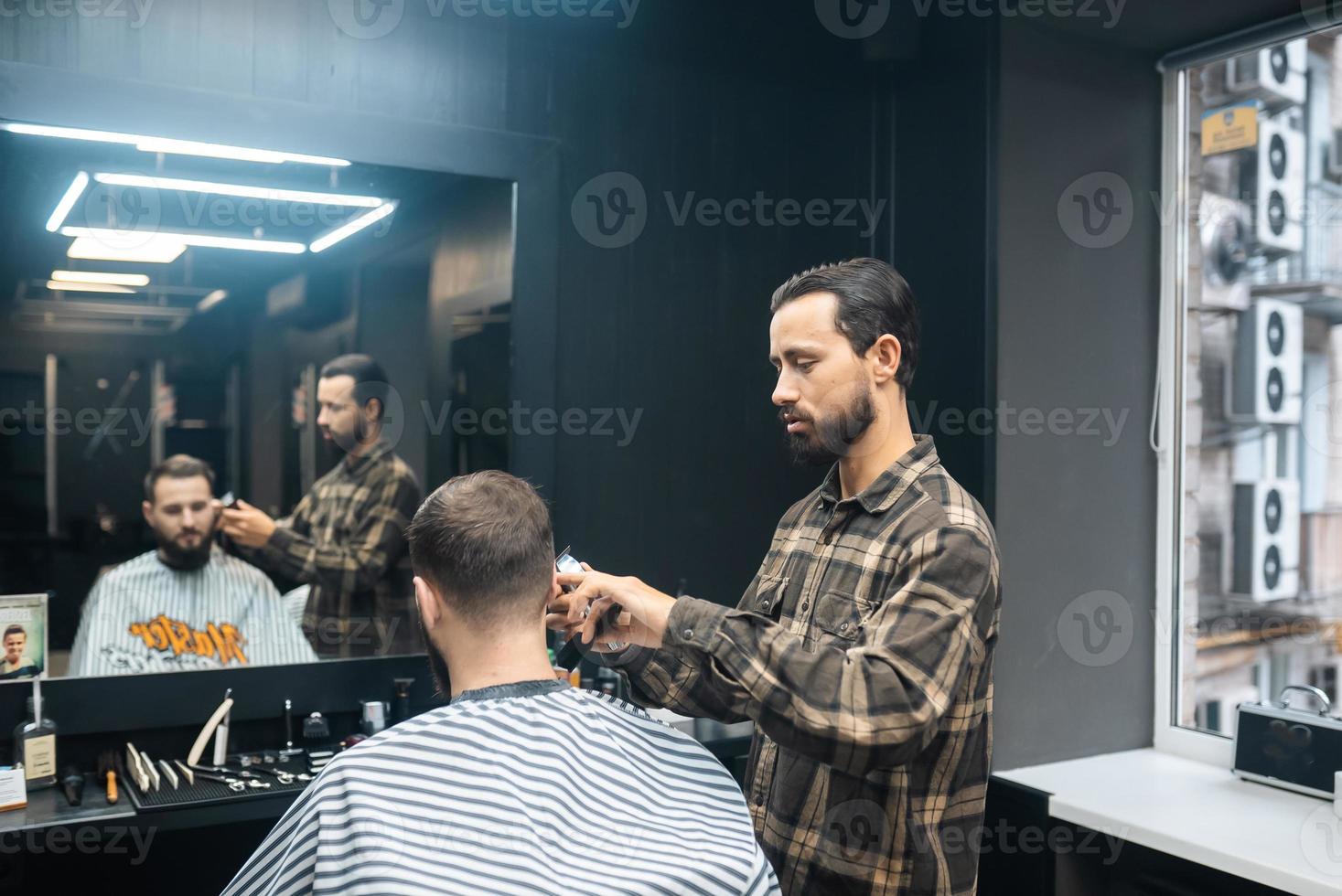 maestro en barbería hace corte de pelo de hombres con cortapelos foto