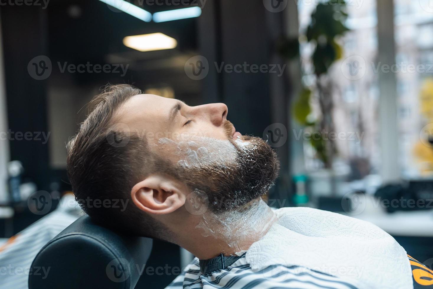 hombre con espuma de afeitar en la cara en una barbería foto