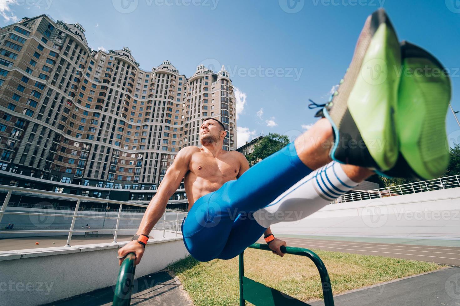 hombre fuerte haciendo ejercicios en barras asimétricas en el gimnasio de la calle al aire libre. foto