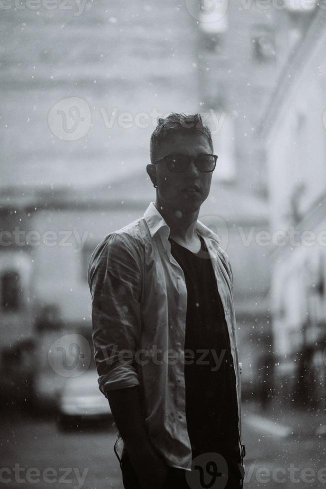 Portrait of carefree handsome young man is feeling free under the rain photo