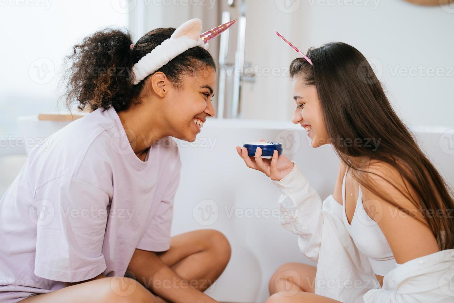 Two girls in the bath playing with face cream photo