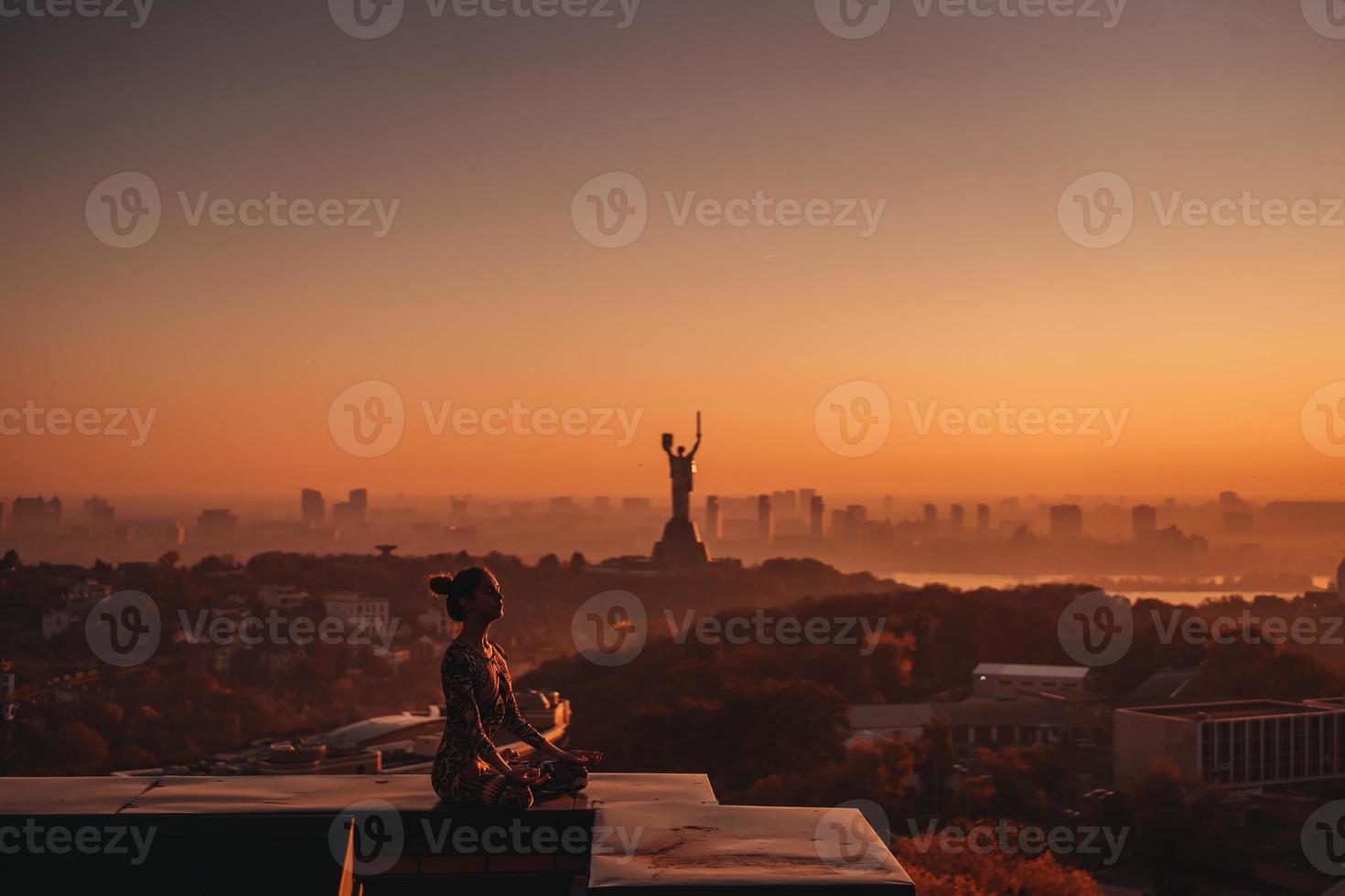 mujer haciendo yoga en la azotea de un rascacielos en la gran ciudad. foto