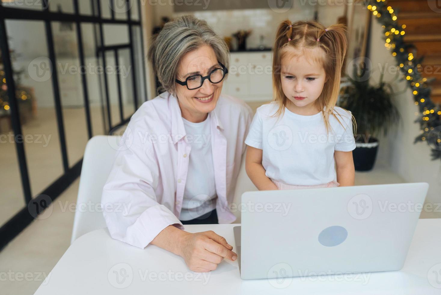 Child and granny looking at the camera with laptop photo