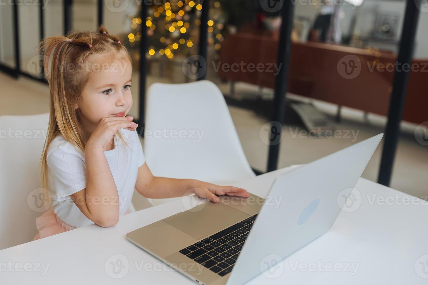 Little girl using tablet computer sitting at table photo