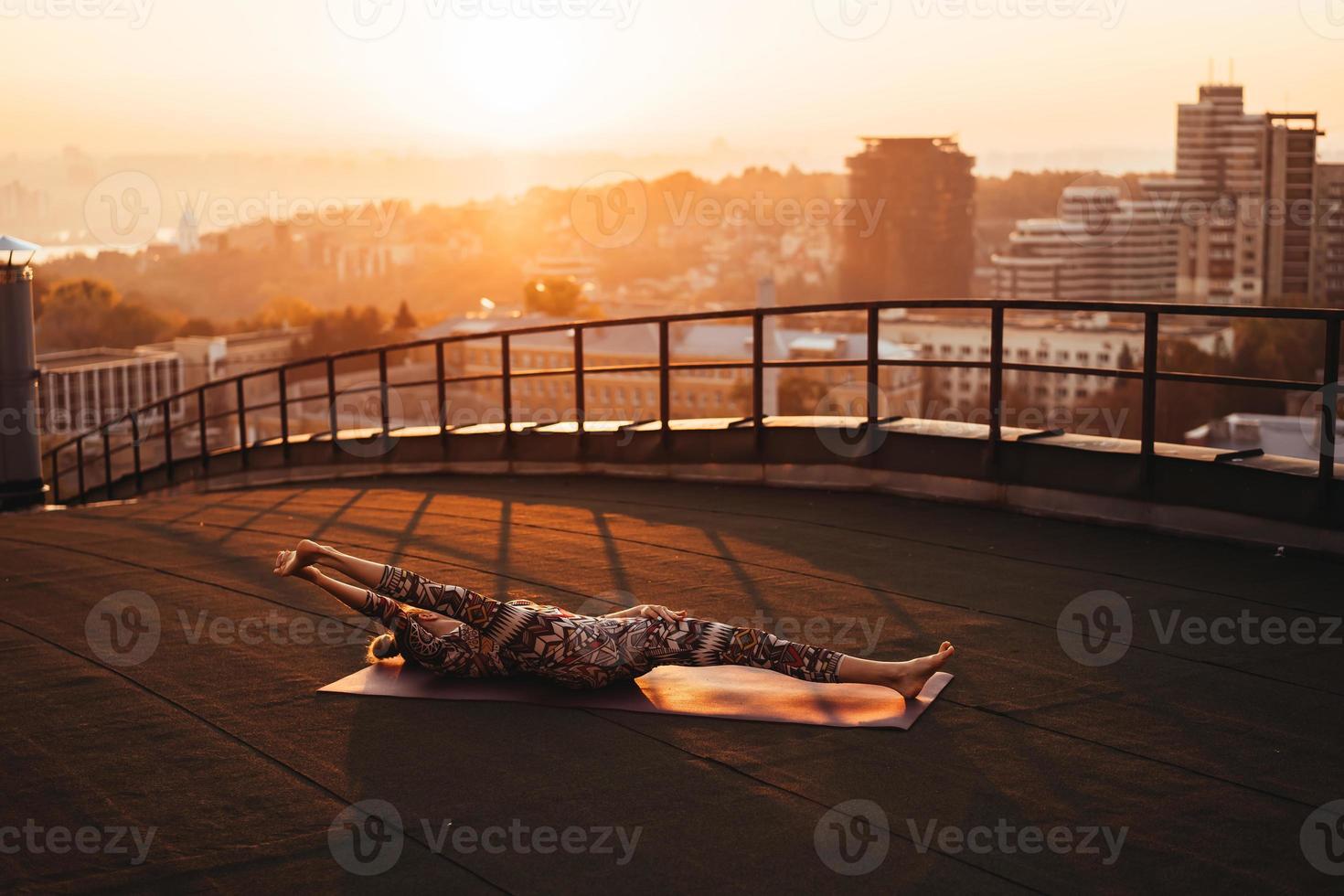 Woman doing yoga on the roof of a skyscraper in big city. photo