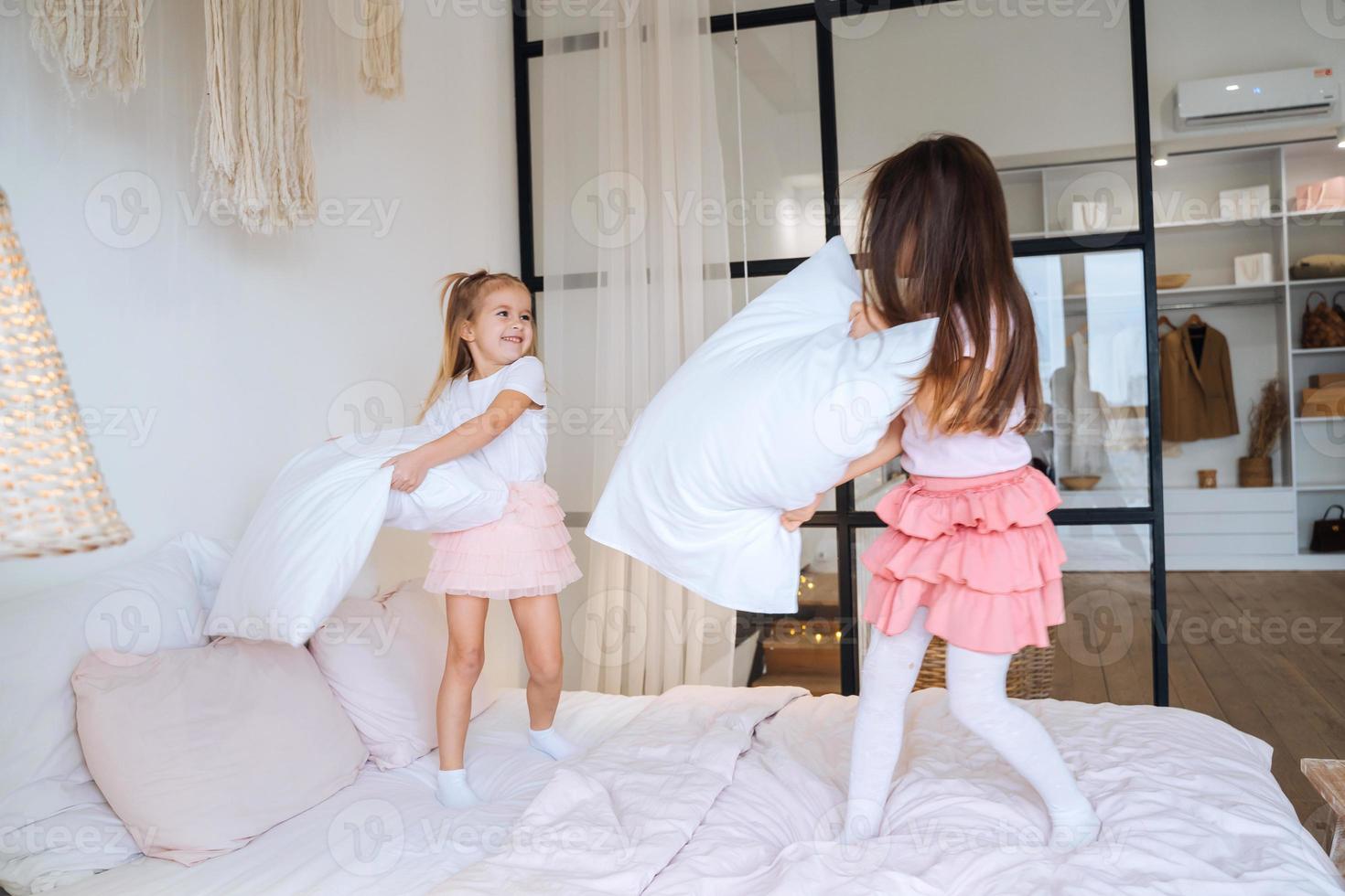 two little girls playing with pillows in bedroom photo