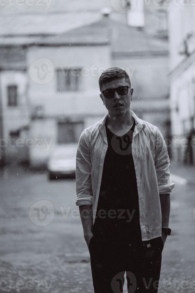 Portrait of carefree handsome young man is feeling free under the rain photo