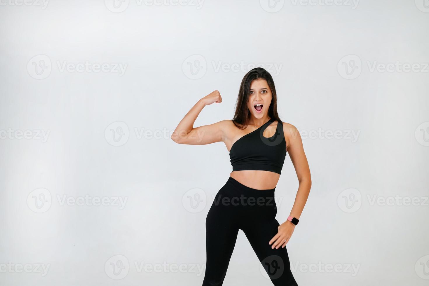 Cheerfully beautiful smiling sporty woman demonstrating biceps photo