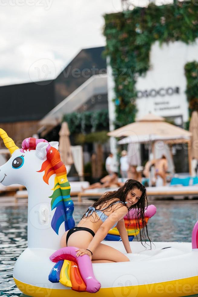 Woman on inflatable unicorn toy mattress float in pool. photo