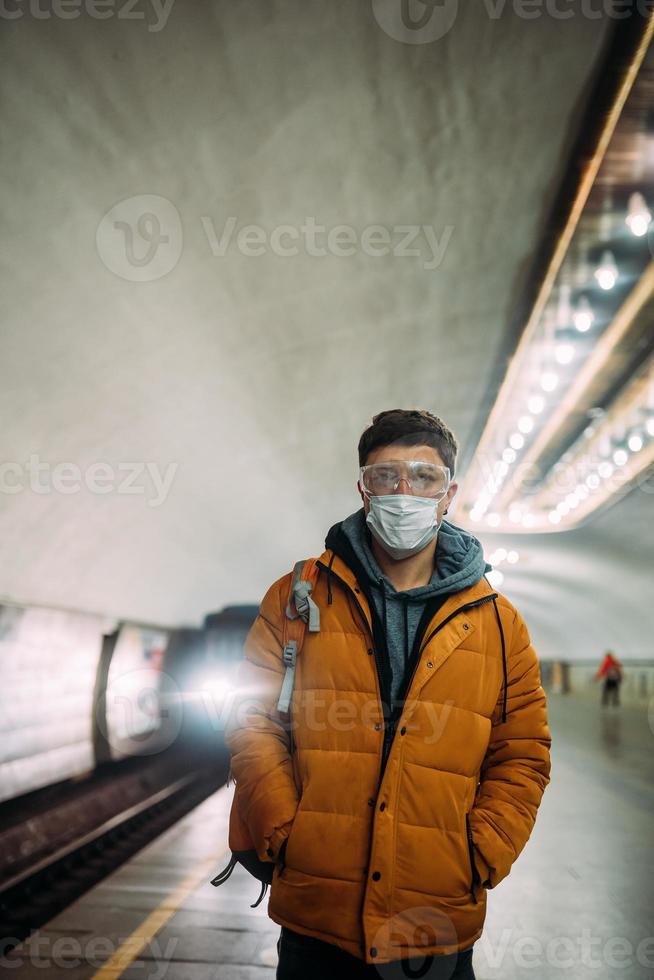 chico parado en la estación con máscara protectora médica en la cara. foto