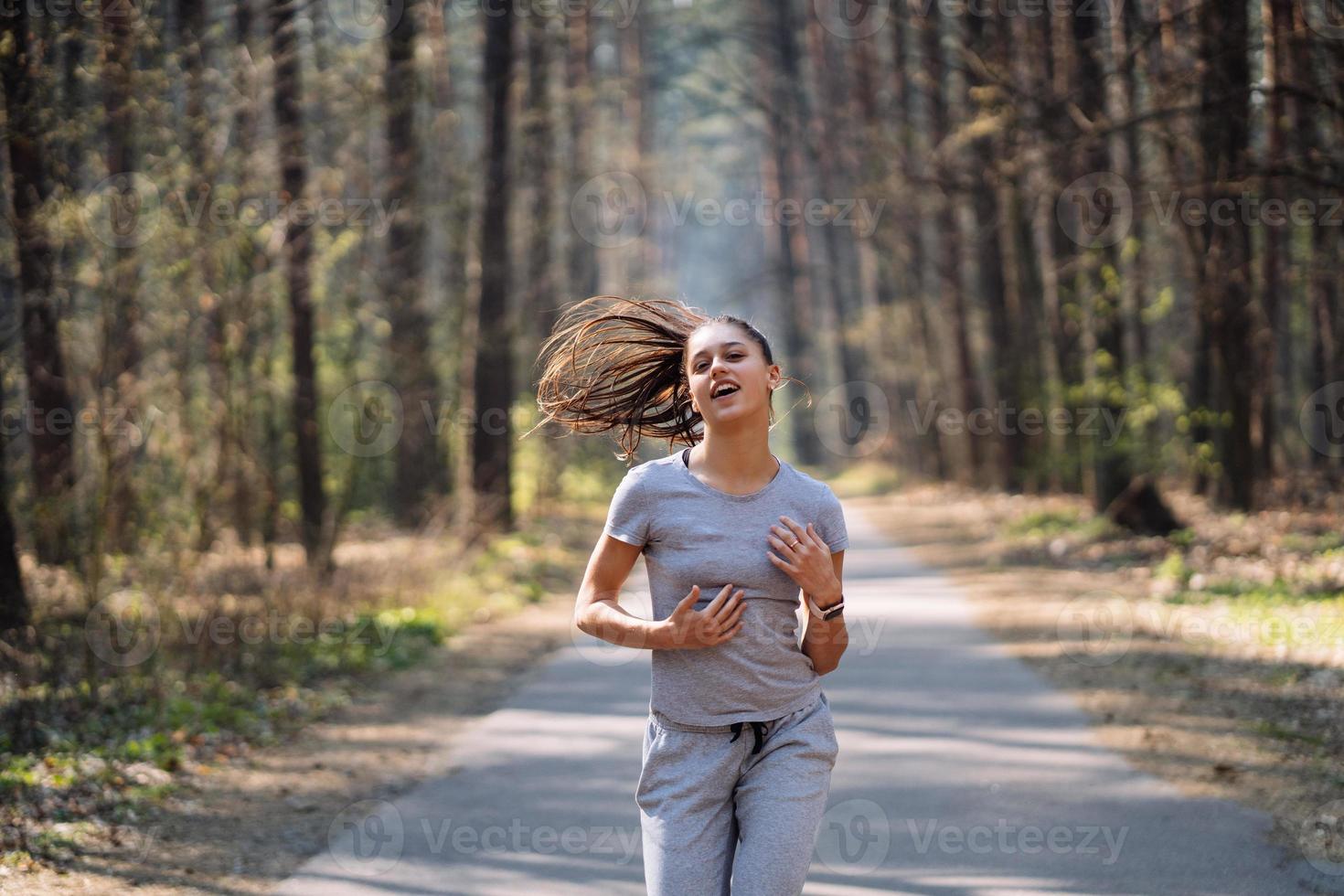Beautiful young woman running in green park on sunny summer day photo