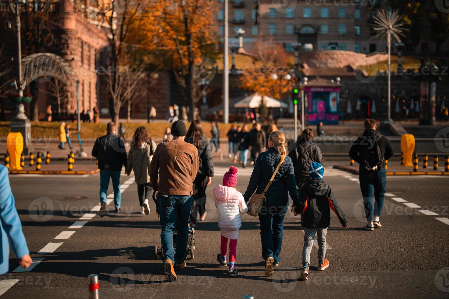 Lots of people crossing the street at the traffic lights. photo