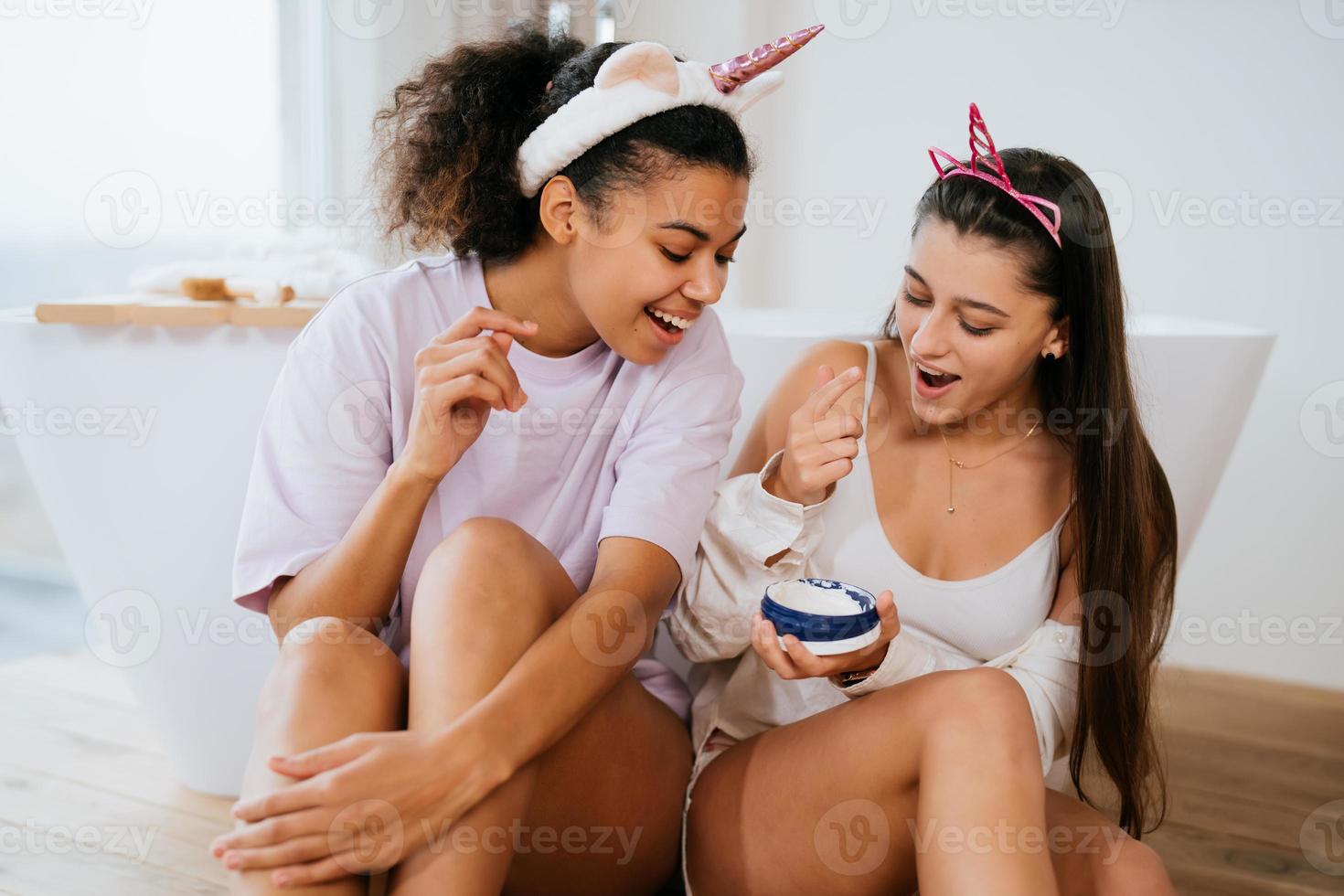 Two girls in the bath playing with face cream photo