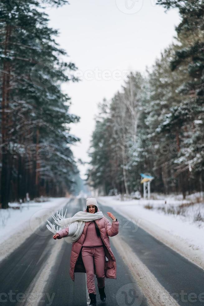 retrato de una hermosa mujer caucásica en un camino a través del bosque nevado foto