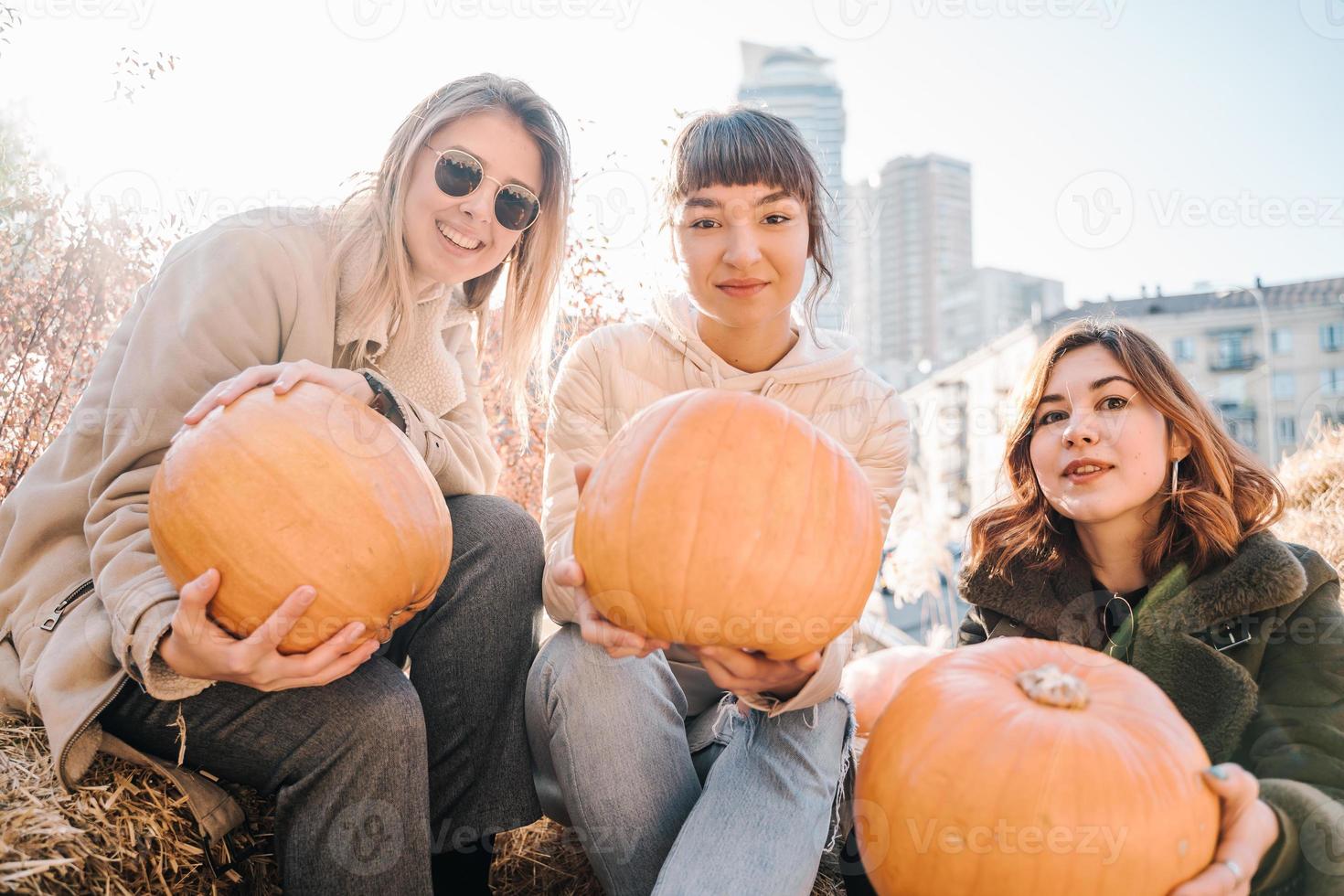 Girls holds pumpkins in hands on the background of the street. photo