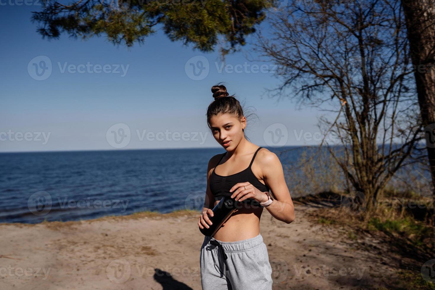 Slim young woman drinking water after training photo