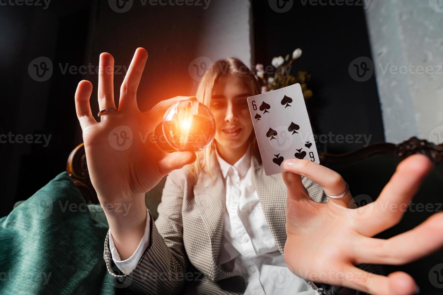 Woman in business suit holding crystal ball and six spade photo
