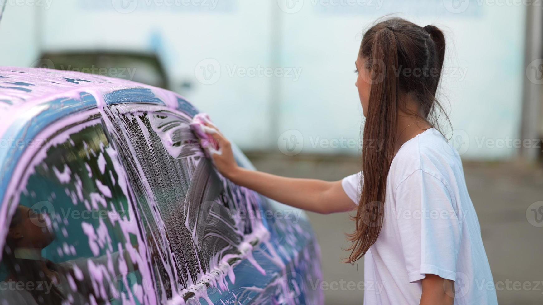 una joven rubia lava su auto foto