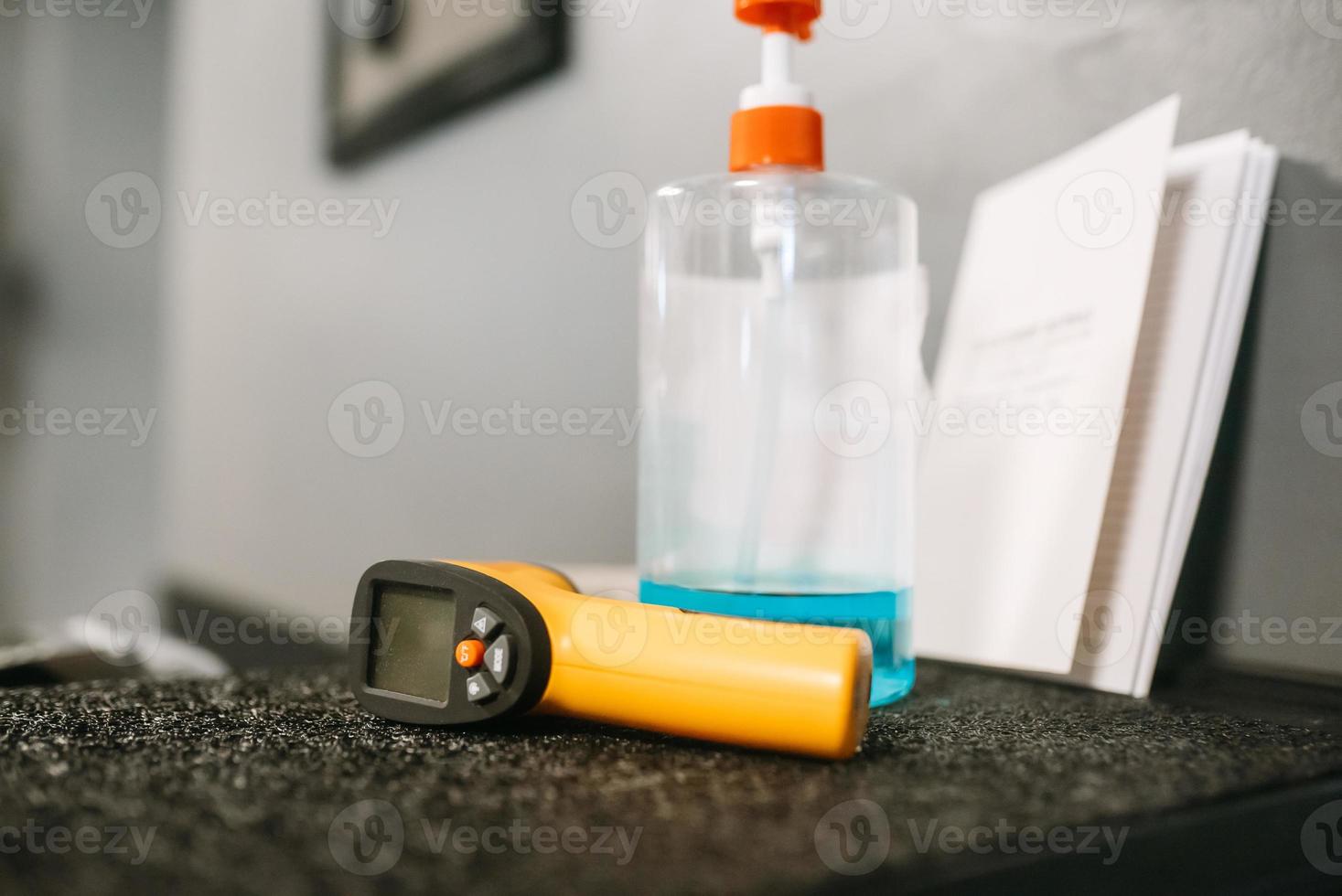 Electronic thermometer and sanitizer gel to wash hands on the table photo