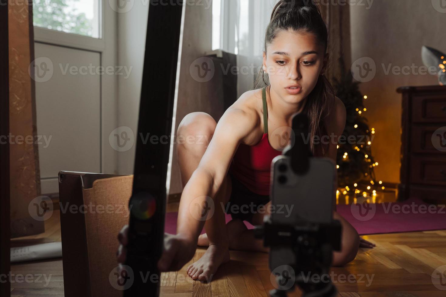 Young woman practicing yoga, is engaged with the teacher online. photo