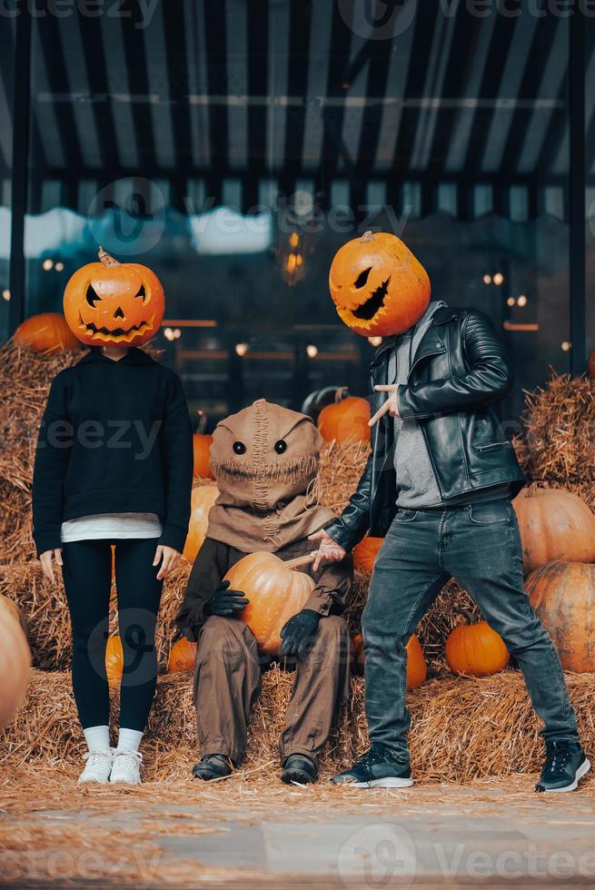 A guy and a girl with a pumpkin heads posing at the scarecrow photo