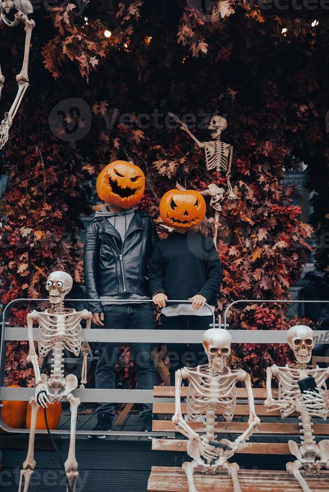 A guy and a girl with a pumpkin heads posing on the street photo