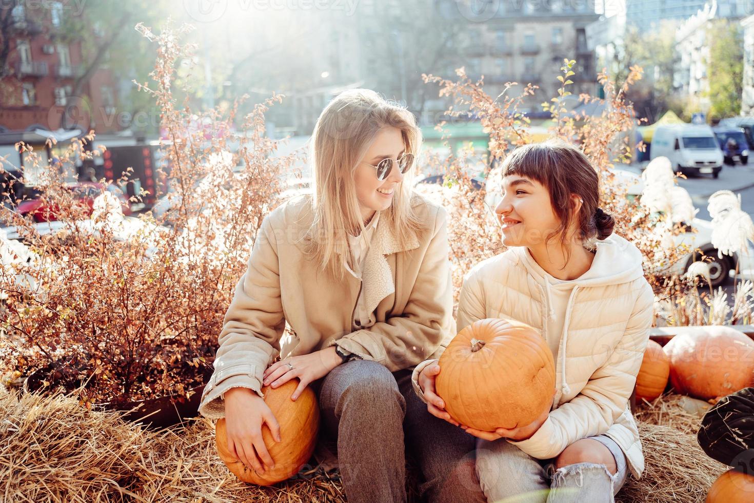 Girls holds pumpkins in hands on the background of the street. photo