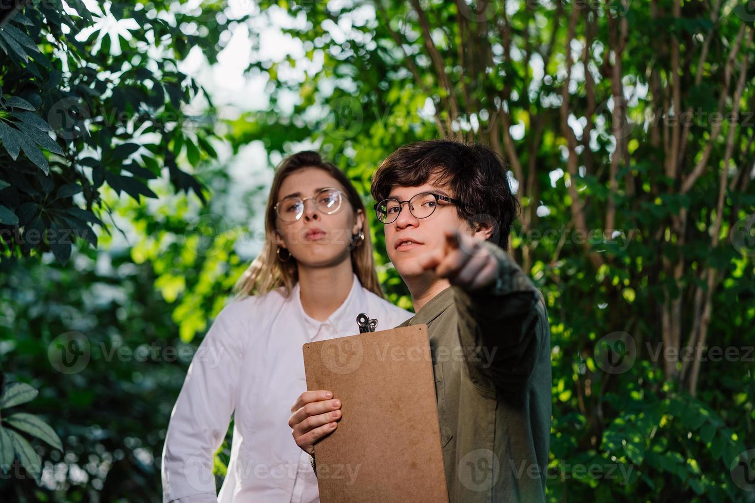 Young agricultural engineers working in big greenhouse photo