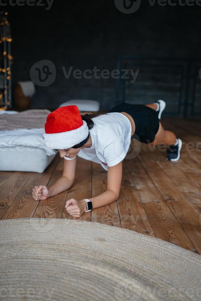 Young woman in santa hat practicing sport gymnastic exercises photo