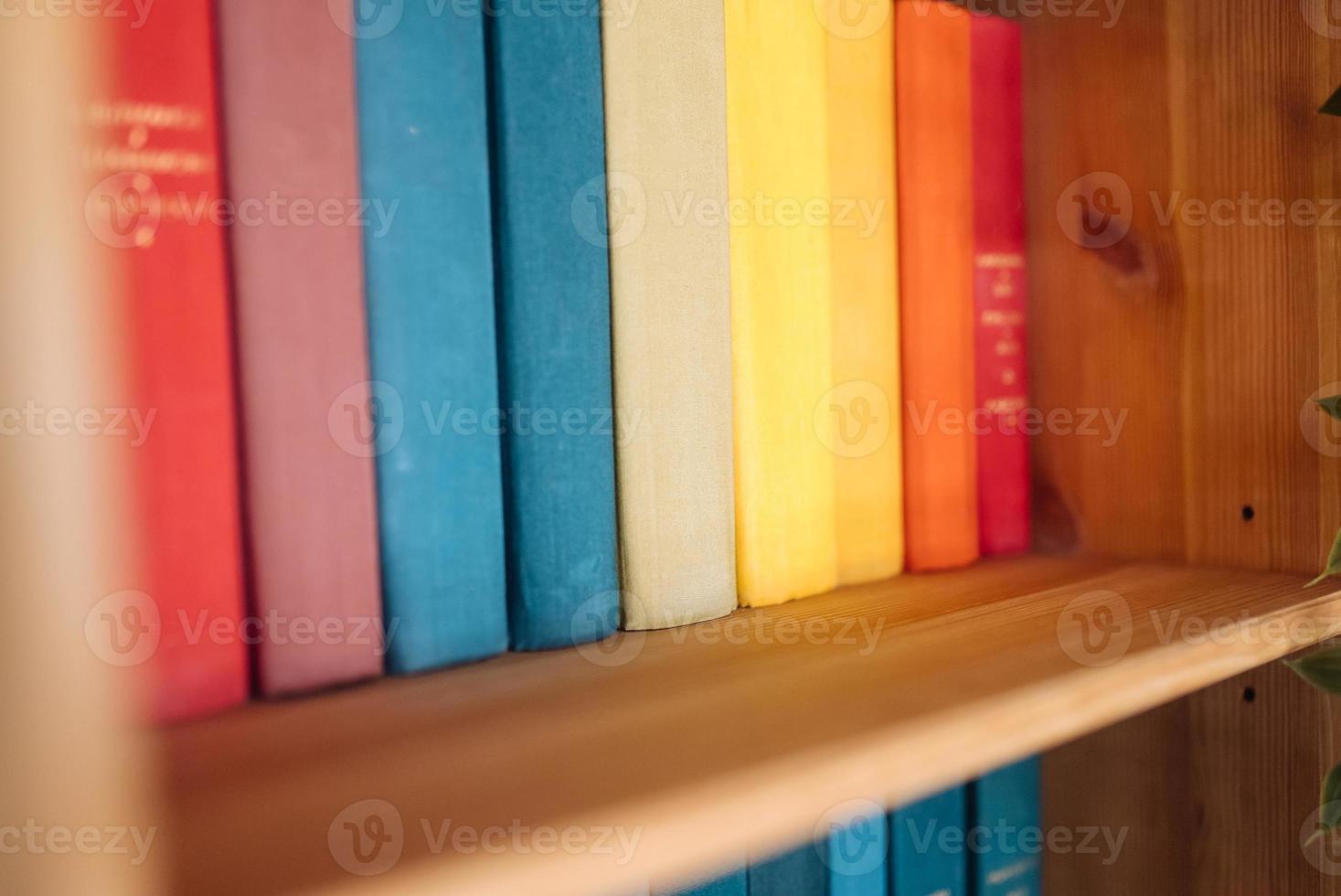 Many books on wooden shelf, close view photo