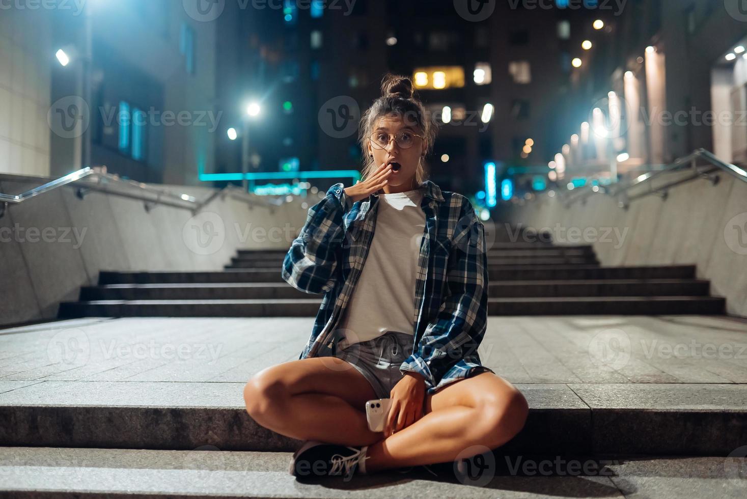 Woman sits on long stone steps in the night city photo