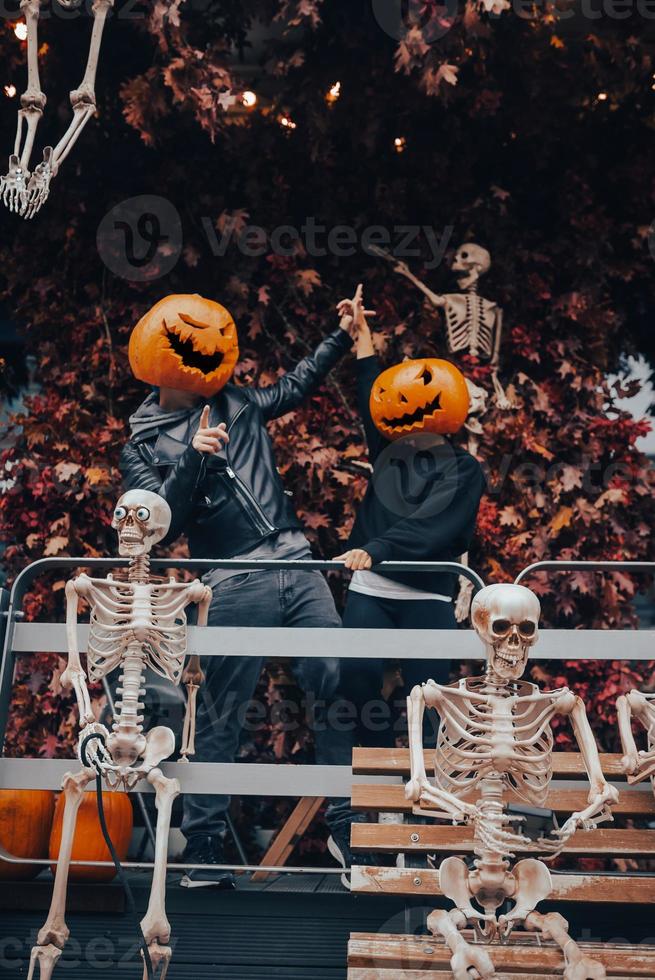 A guy and a girl with a pumpkin heads posing on the street photo