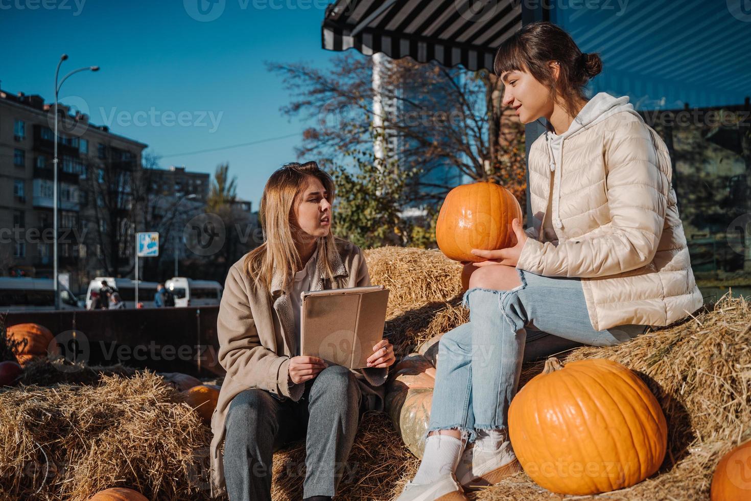 Girls have fun among pumpkins and haystacks on a city street photo