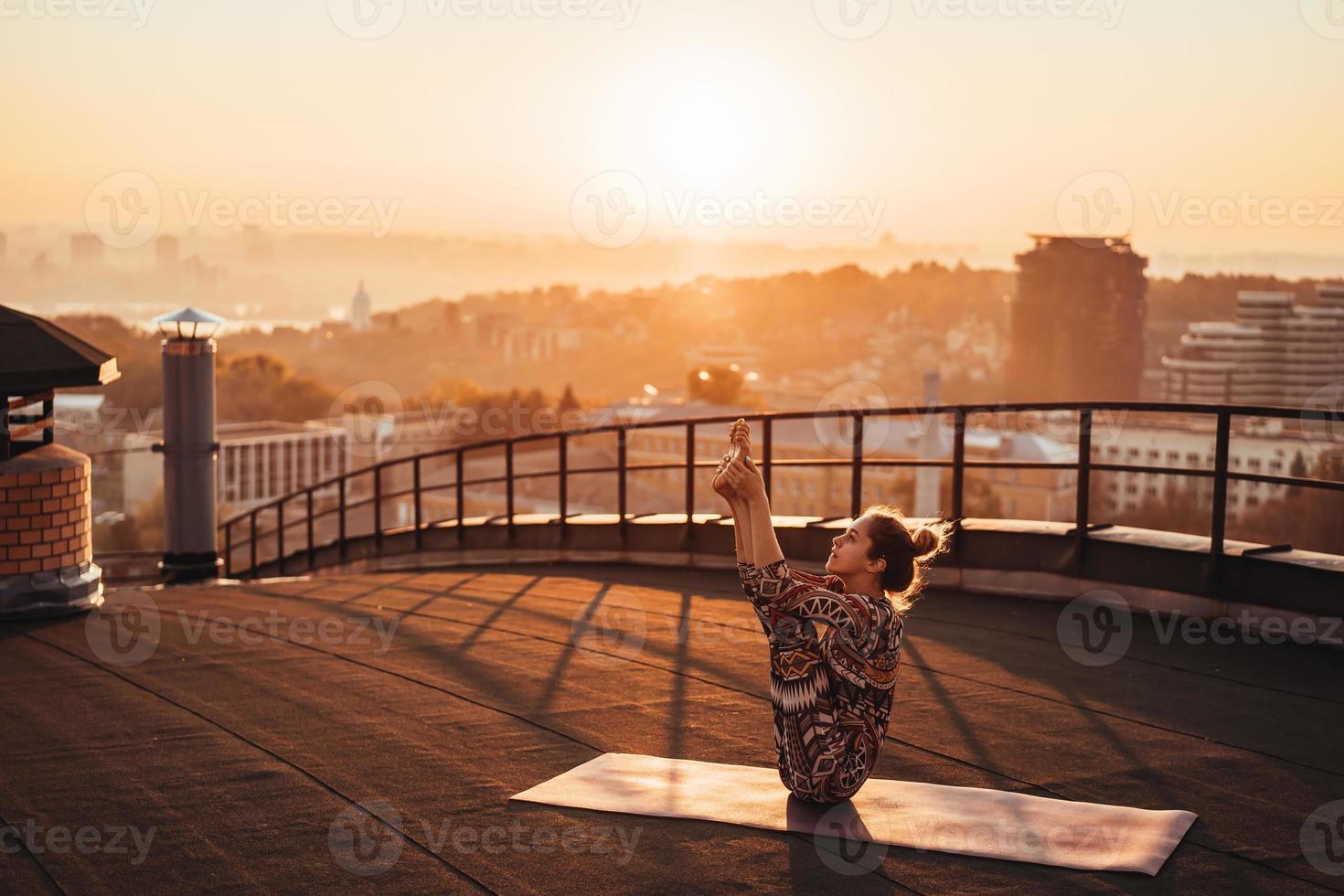 mujer haciendo yoga en la azotea de un rascacielos en la gran ciudad. foto