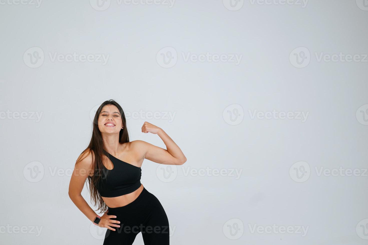 Cheerfully beautiful smiling sporty woman demonstrating biceps photo