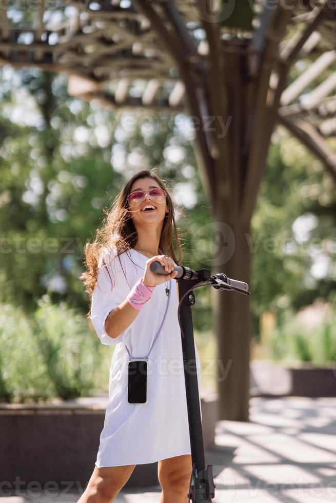 Young beautiful woman and an electric scooter, ecological transport photo