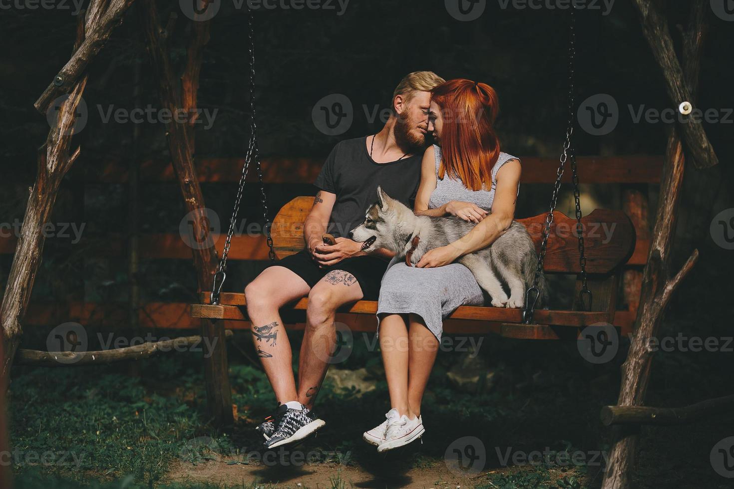 beautiful couple together with dog on a swing photo