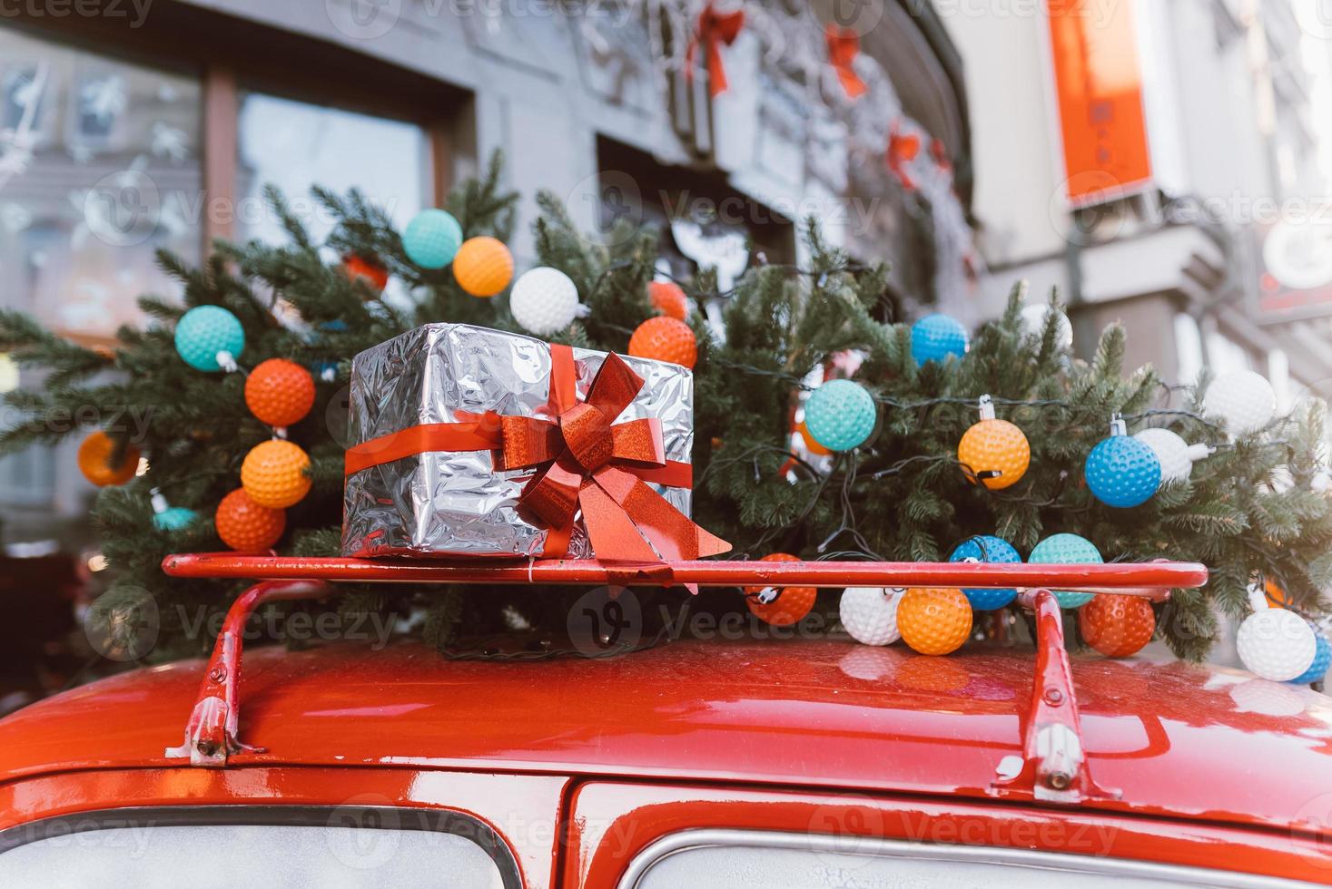 Red retro car with a Christmas tree fir tied to the roof. photo