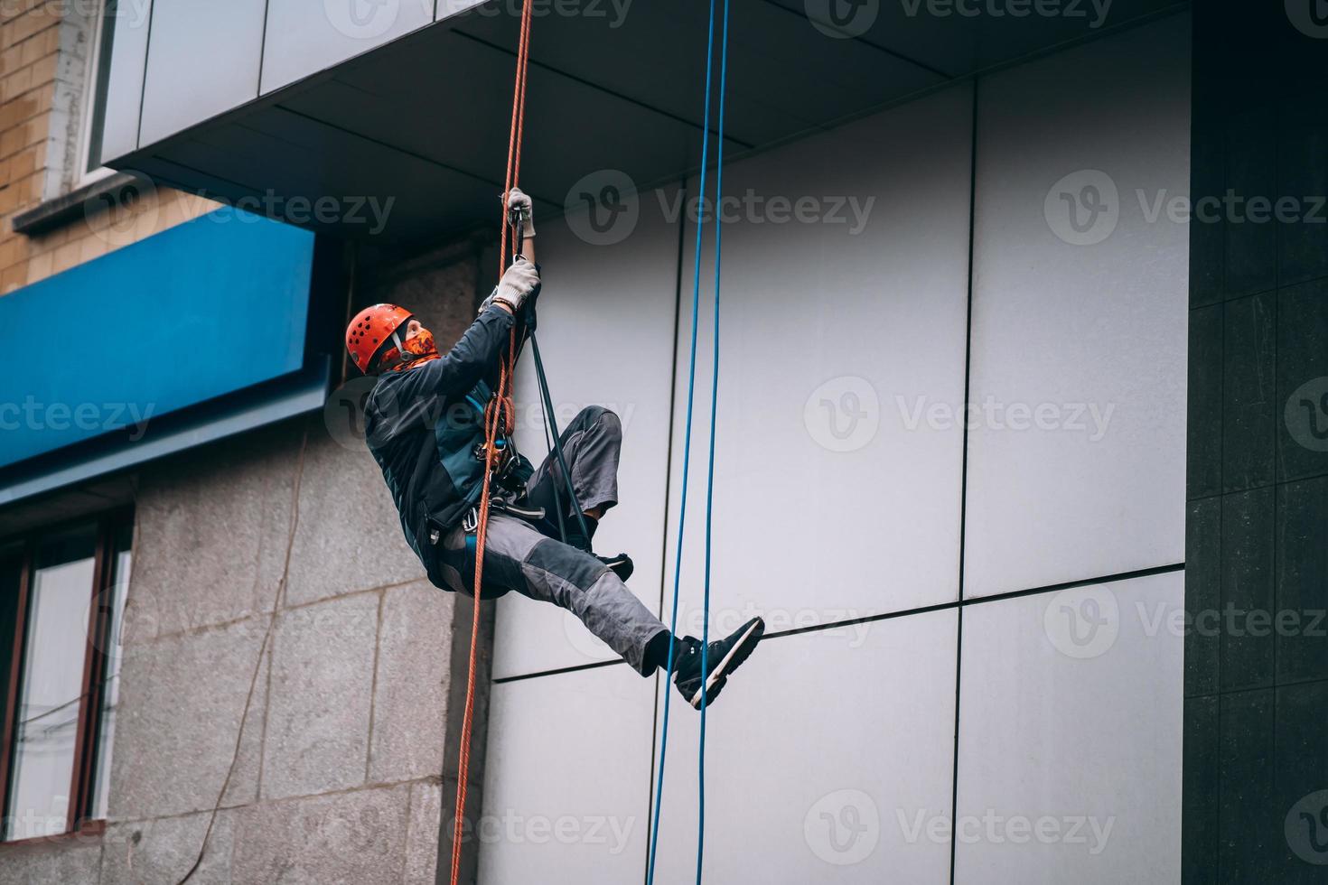 Industrial climber in uniform and helmet rises photo